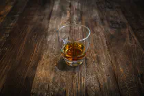 A glass of whiskey on a wooden bar or table